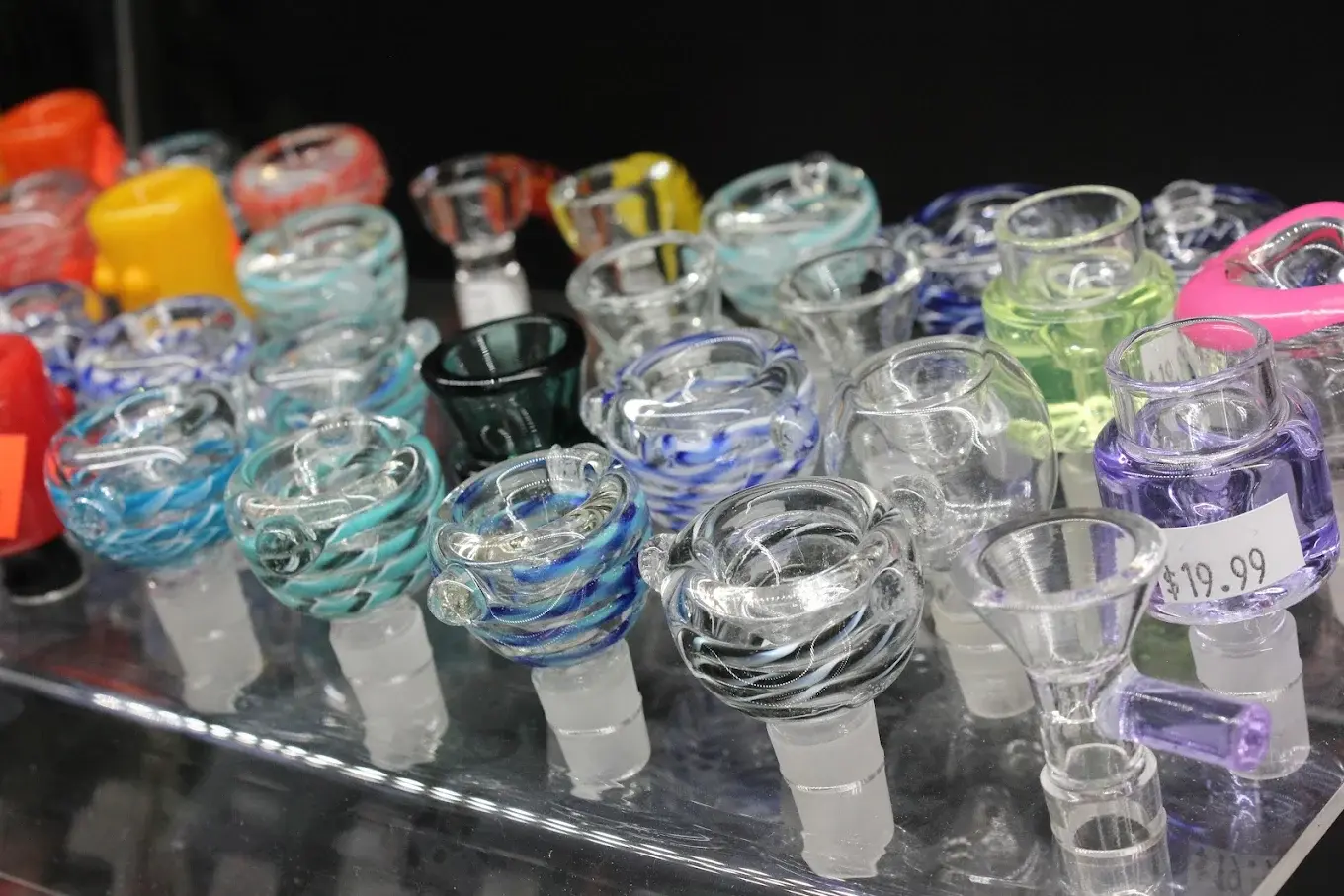 Tray of colorful glass bowl pieces priced on a display shelf.